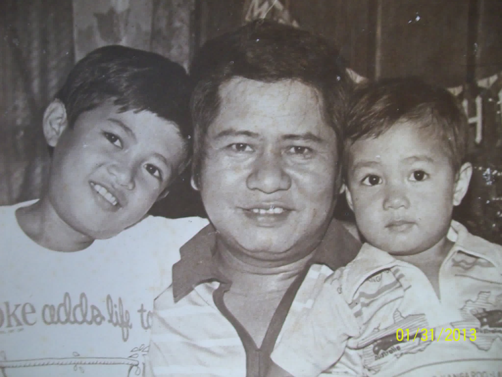 A black-and-white family portrait of a man between two young children.