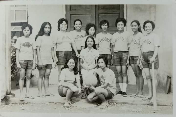 Ten women pose as a group, several wearing matching shirts and shorts.