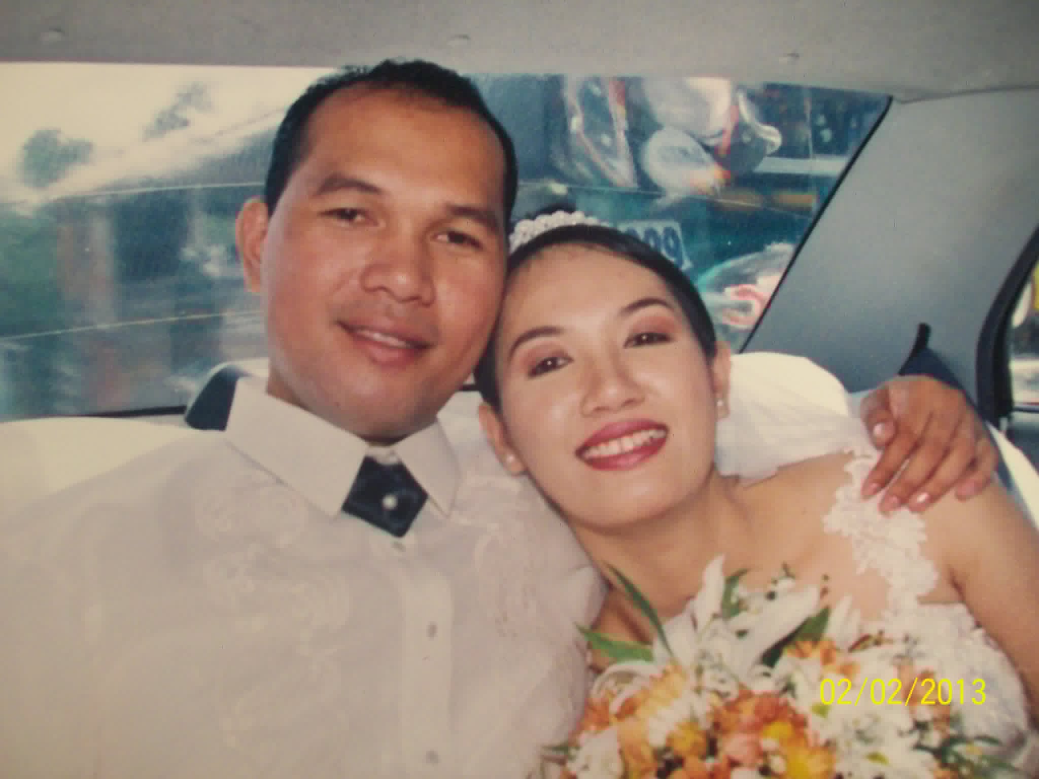 A bride and groom smile together inside a motor vehicle.